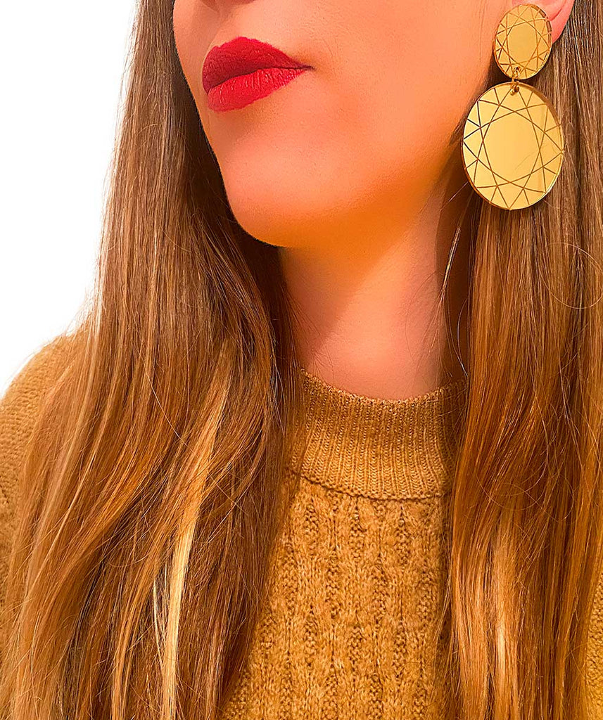 Mujer con pendientes de metacrilato geométricos circulares dorados.